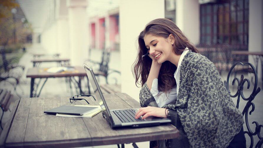 smiling young woman with laptop outdoors