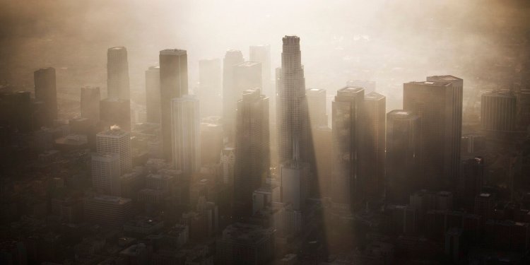 Dramatic rays of light beam through the Los Angeles skyline as the sun sets and the marine layer rolls in.