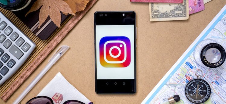 instagram logo on a smartphone surrounded by travel gear