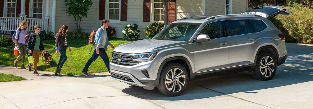 2021 VW Atlas grey exterior driver side front parked with tailgate open family walking toward with bags o