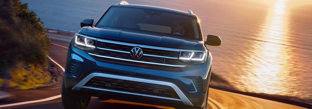 2021 Volkswagen Atlas blue driving toward shot with sunset water behind o